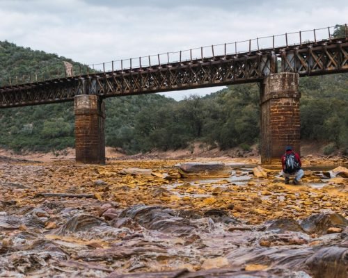 young-photographer-with-backpack-cap-photographing-old-iron-bridge-rio-tinto_181624-50560